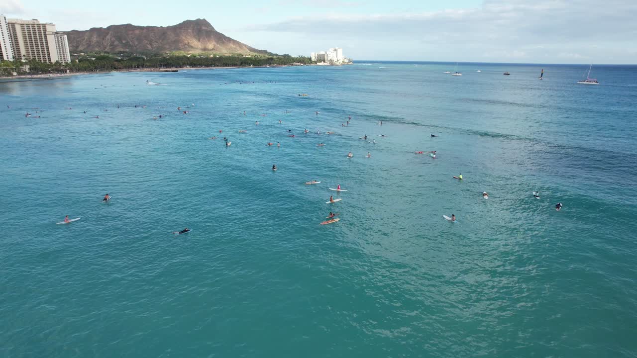 Surfisti aspettano le onde in una popolare località per il surf su una spiaggia tropicale.