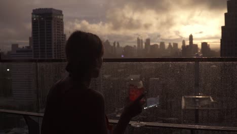 attractive young woman having a drink on a rooftop bar in bangkok thailand