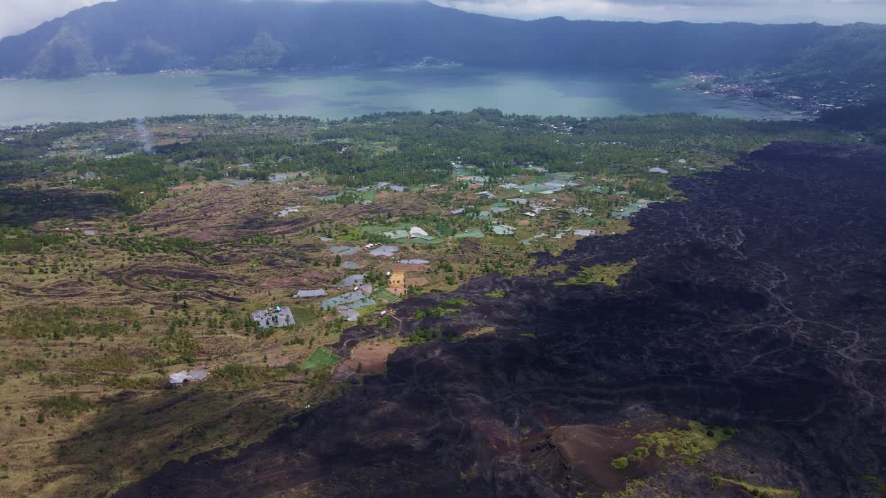 vista aérea de las tierras cultivadas cerca del lago batur con el volcán gangung batur al fondo en bali, indonesia