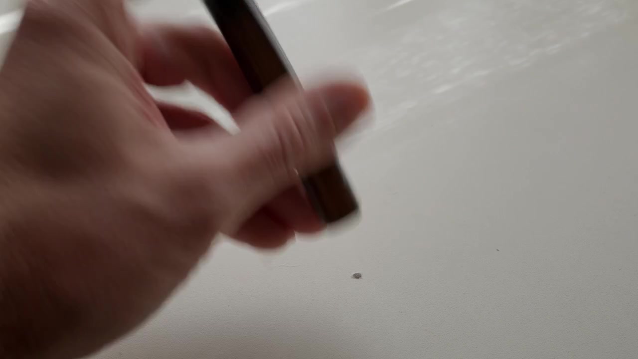 Hand quickly rotating a marker on clean white tabletop in closeup indoor footage