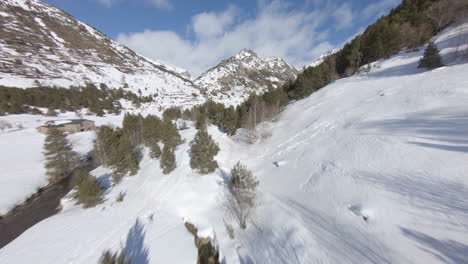 Drone-flying-over-snowy-Incles-valley-with-Pyrenees-mountain-range-in-background,-Andorra