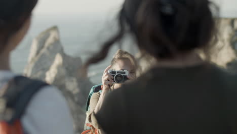 mujer sonriente tomando una foto de su hija parada en el borde del acantilado