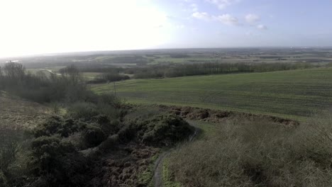 Idyllic-British-farming-meadows-countryside-fields-aerial-view-pull-back-reveal-of-panoramic-landscape