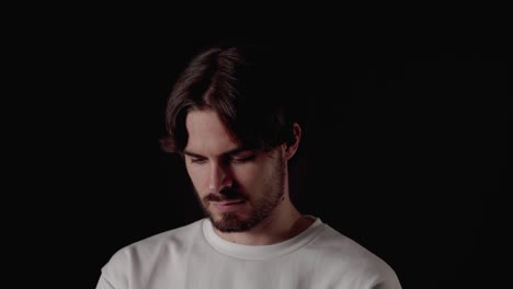 trendy young man using and typing annoyed on phone, close, black background