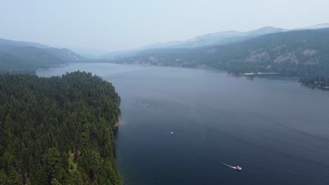 drone shot of forest on the shore of lake payette with mountains in the background