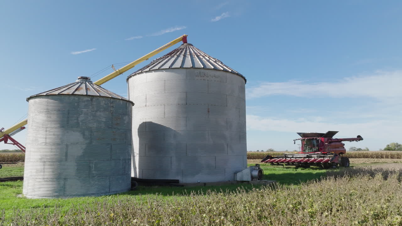 silos de contenedores de grano y cosechadora combinada en un campo agrícola rural, aérea