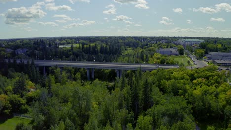 clouds block the sun at an international bridge with many country flags on it. as the clouds passover, the bridge is naturally lit, surrounded by lush green forest parks at a small town subburb