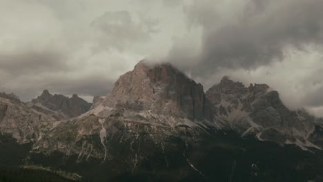aerial view with distant steep tall mountains touching the clouds green forest at the bottom, alps rocky mountains, before storm, rainy day, cinematic grade
