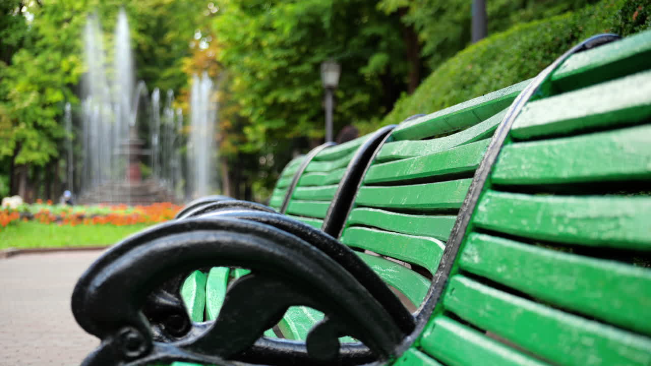 View of the Stefan cel Mare Central Park in Chisinau, Moldova. Green benches with working fountain on the background, walking people and greenery