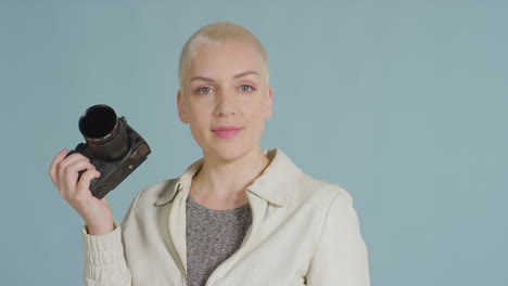 Female-caucasian-model-posing-with-DSLR-against-blue-backdrop-01