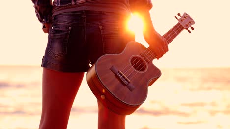 woman at sunset holding a ukulele