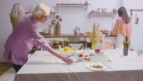 madre, hija y abuelas quitando los platos de la mesa después de la cena familiar