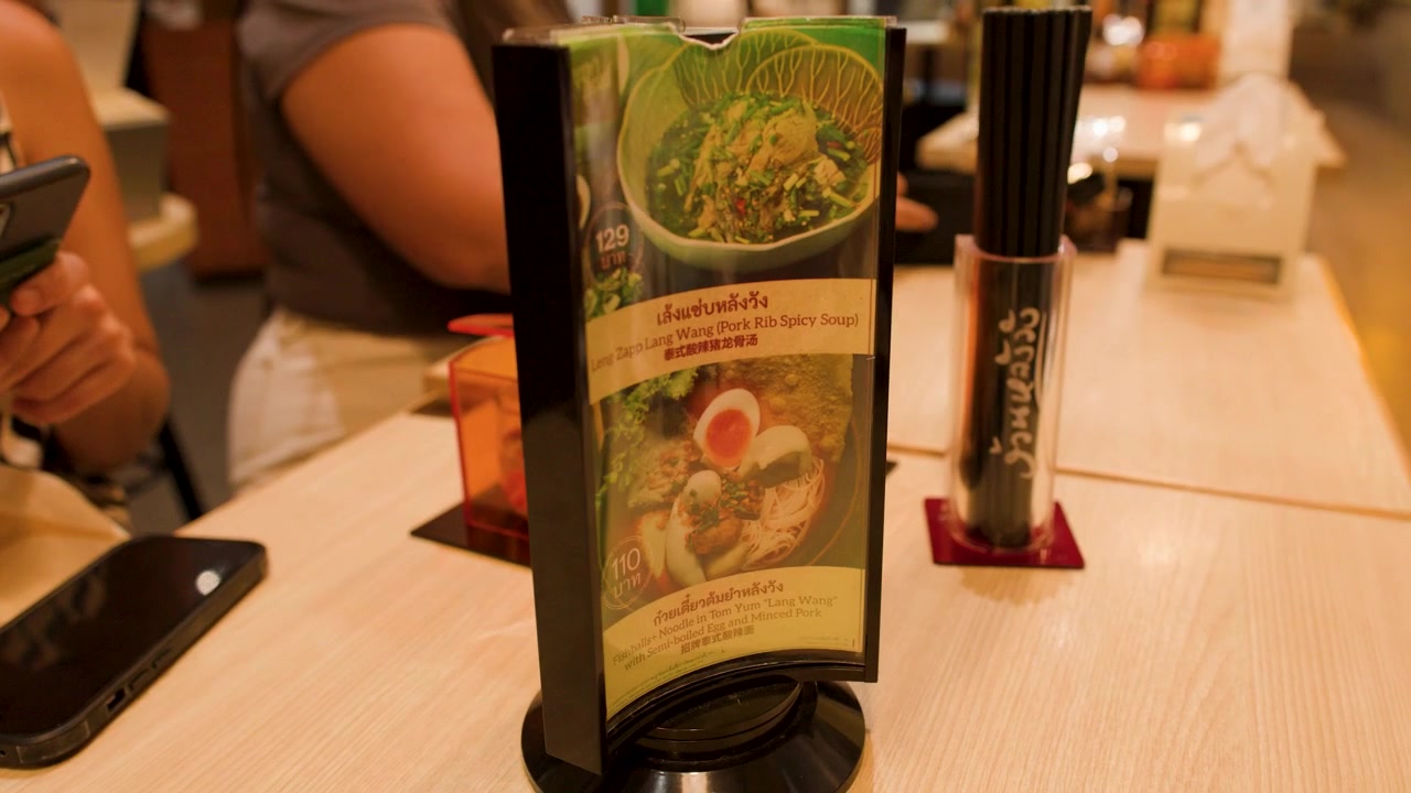 Tayland'ın Bangkok kentindeki bir erişte restoranında müşteri dönen masa üstü menüsünü işaret ediyor