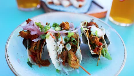 hand reaching for tacos with beer nearby