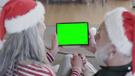 Pareja-Mayor-Caucásica-Teniendo-Videollamada-De-Tableta-Navideña-Con-Pantalla-Verde,-Cámara-Lenta