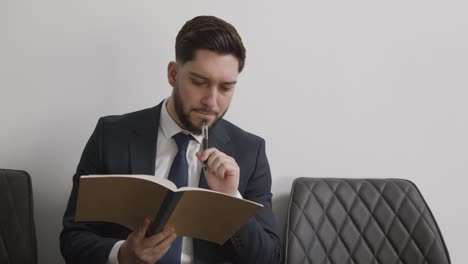 Male Candidate Wearing Suit In Office Checking Notes Before Job Interview