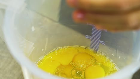 cocinar rompiendo huevos sobre una jarra de medición