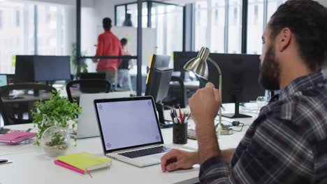hombre de negocios de raza mixta sentado en un escritorio usando una computadora portátil con espacio de copia