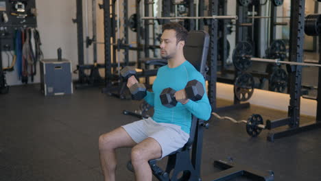 portrait of a european guy doing seated dumbbell bicep curls in a gym