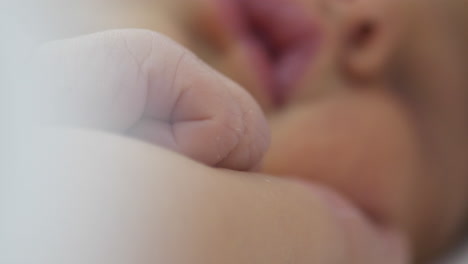 bebé recién nacido moviendo los dedos lentamente mientras duerme, vista de cerca