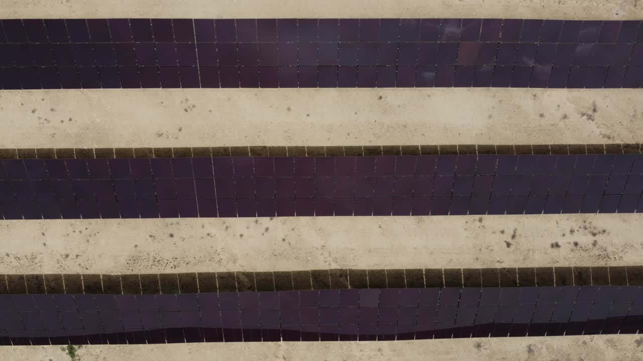 Drone slowly pans out over rows of solar panels in a solar energy generation farm also called solar park