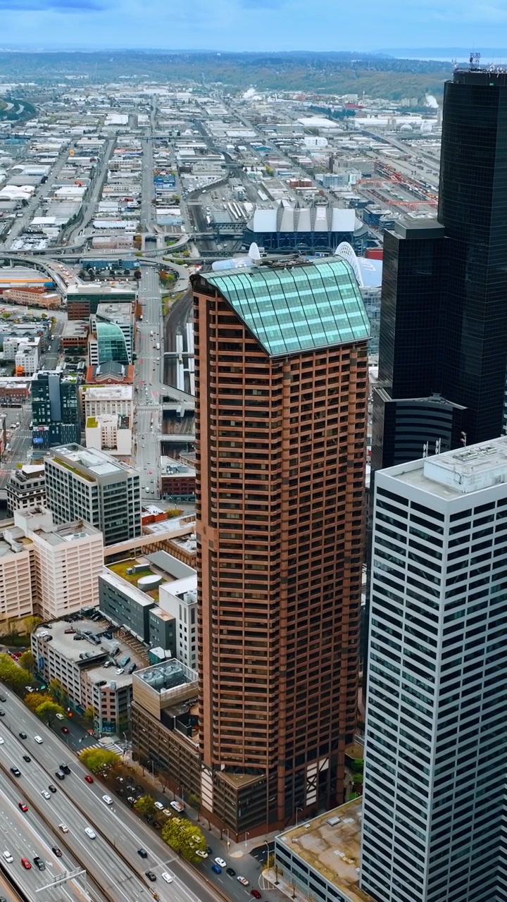 Traffico vivace sulle autostrade a più corsie di Seattle, Stato di Washington, USA. Grattacieli nel centro della città e architettura a bassa altezza sullo sfondo. Vista dall'alto. Video verticale