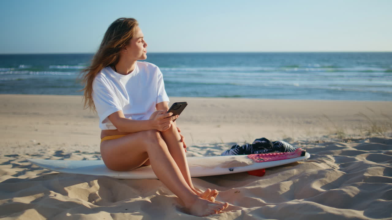 Vacation lady browsing smartphone warming sunlight at beach. Surf girl messaging