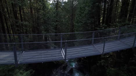 flying over suspension bridge to reveal rushing forest mountain stream