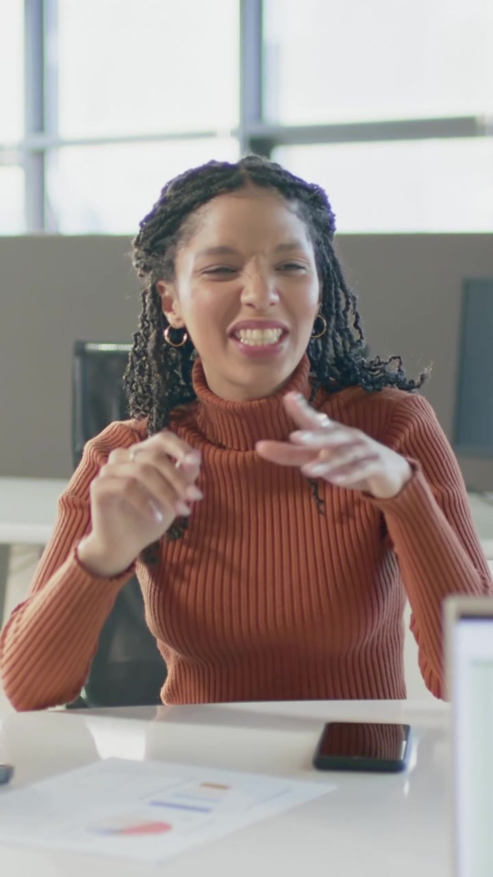 Vertical video: Starting chat, office pro in rust top explaining charts and tapping phone at desk
