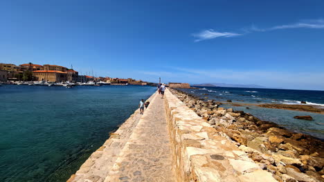 aerial view of people walking along the sea walls of the old harbor in chania, crete, greece.