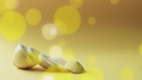 composition of spots of light over sliced lemon on yellow background