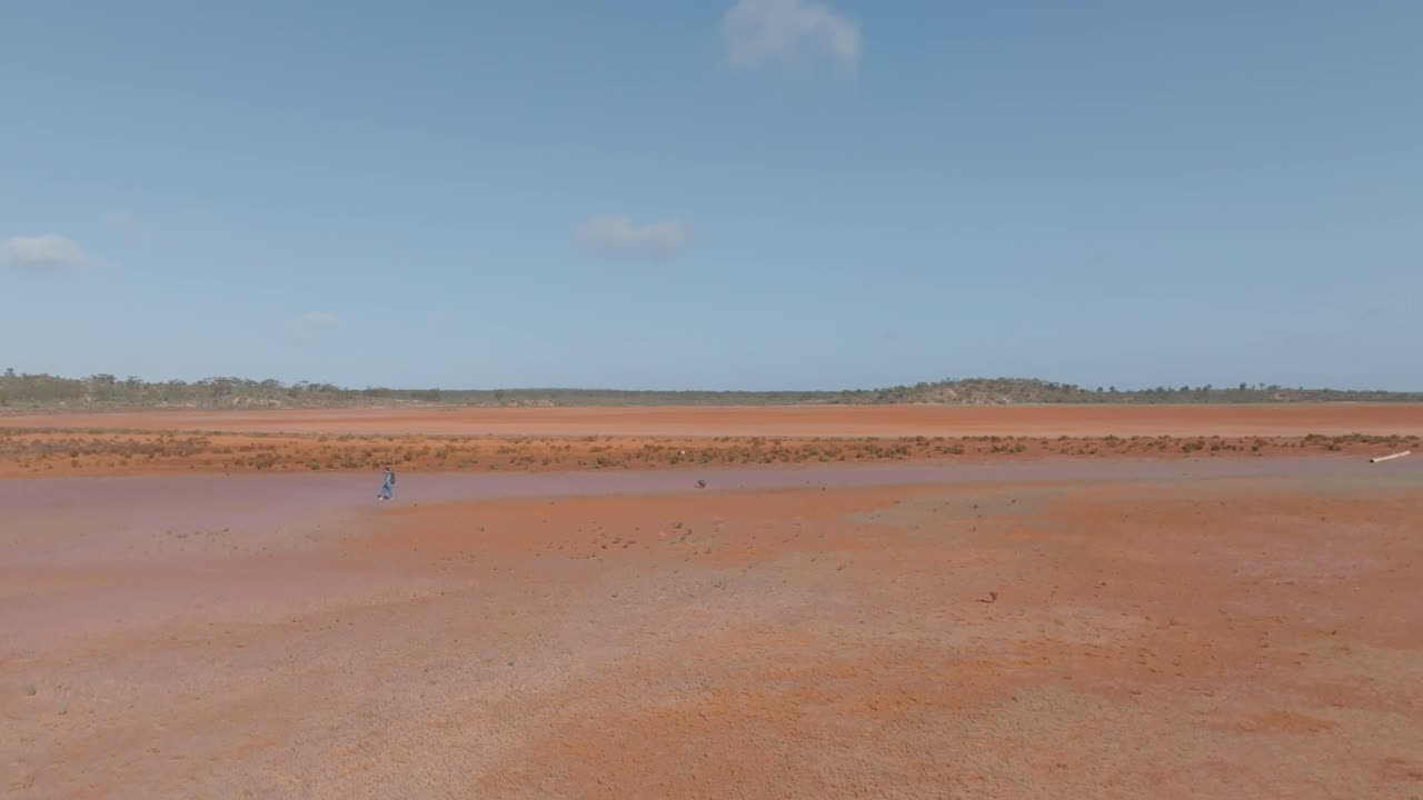 Person Walking Across a Vast Red Desert Landscape