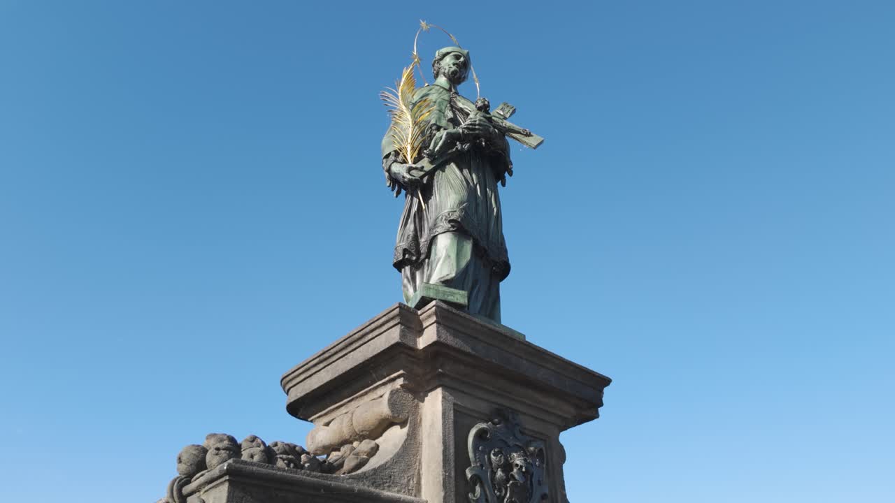 Statue of St. John of Nepomuk on the Charles Bridge in Prague, Czechia, under a clear blue sky
