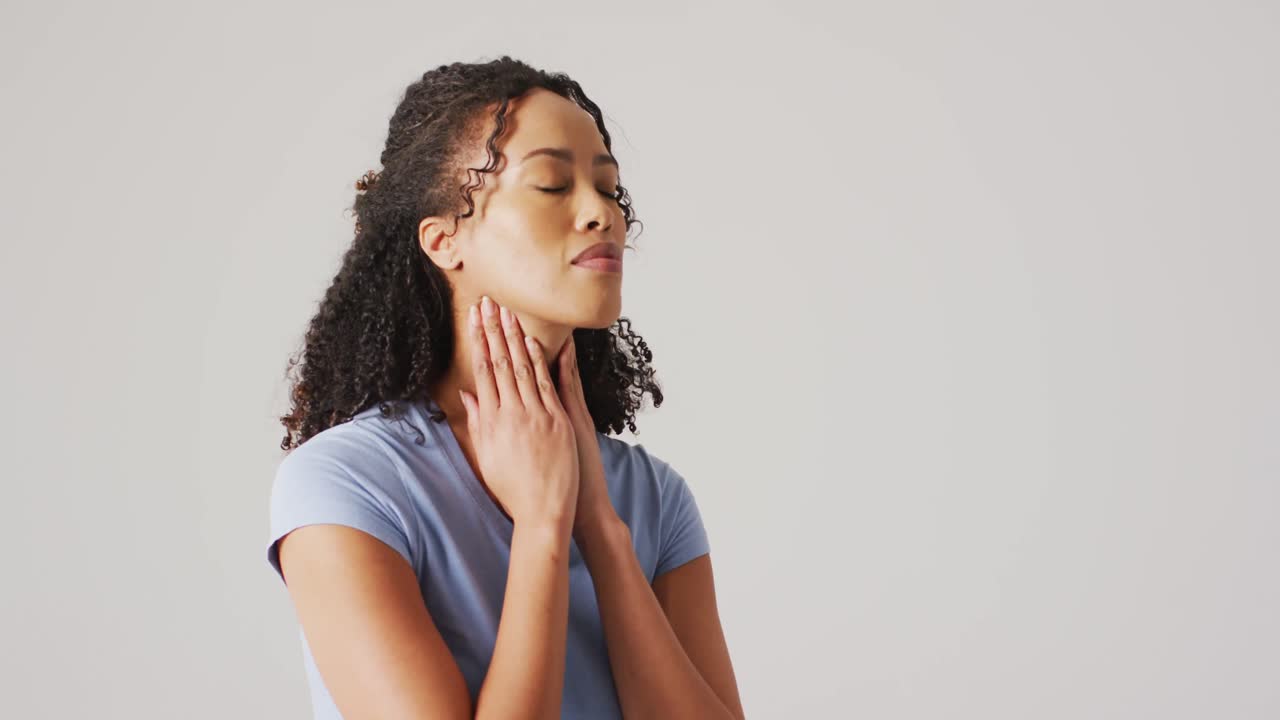 video de una mujer biracial tocando su cuello sobre un fondo blanco