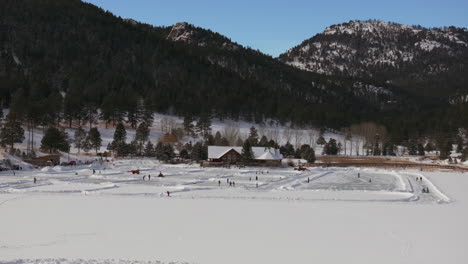 Patinaje-Sobre-Hielo-Patinar-Pista-De-Hockey-Lago-Estanque-Hockey-Invierno-Etown-Casa-Del-Lago-De-Hoja-Perenne-Denver-Campo-De-Golf-Colorado-Aéreo-Cinematográfico-Zumbido-Soleado-Cielo-Azul-Mañana-Invierno-Fresco-Nieve-Lentamente-Hacia-Atrás-Movimiento