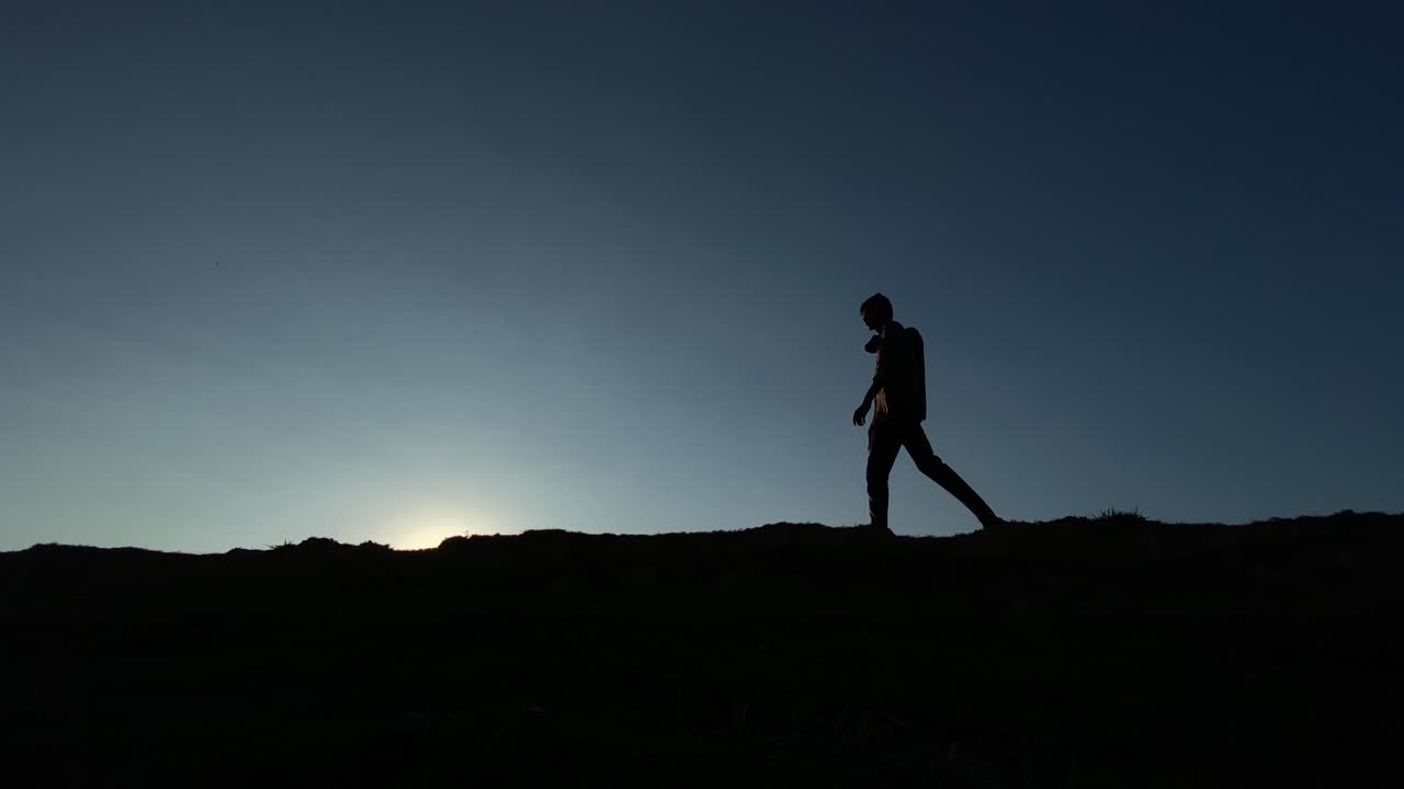 어두운 하늘 배경에서 밤에 걷는 알 수 없는 남자의 실루엣