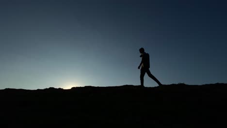 Silueta-De-Un-Hombre-Desconocido-Que-Camina-De-Noche-En-El-Fondo-Del-Cielo-Oscuro