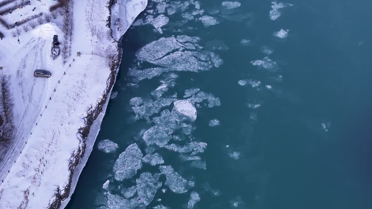 Aerial top down of flowing ice floe on Selfoss River in Iceland. Snowy winter day with parking car. Global warming and melting concept theme.