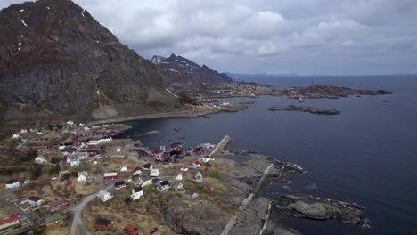 Aerial-backwards-shot-of-the-fishing-village-A-in-Lofoten-with-Sorvagen-in-the-background-on-a-cloudy-winter-day