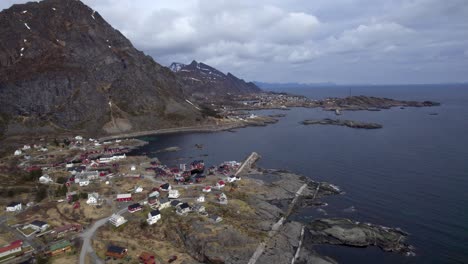 aerial backwards shot of the fishing village a in lofoten with sorvagen in the background on a cloudy winter day