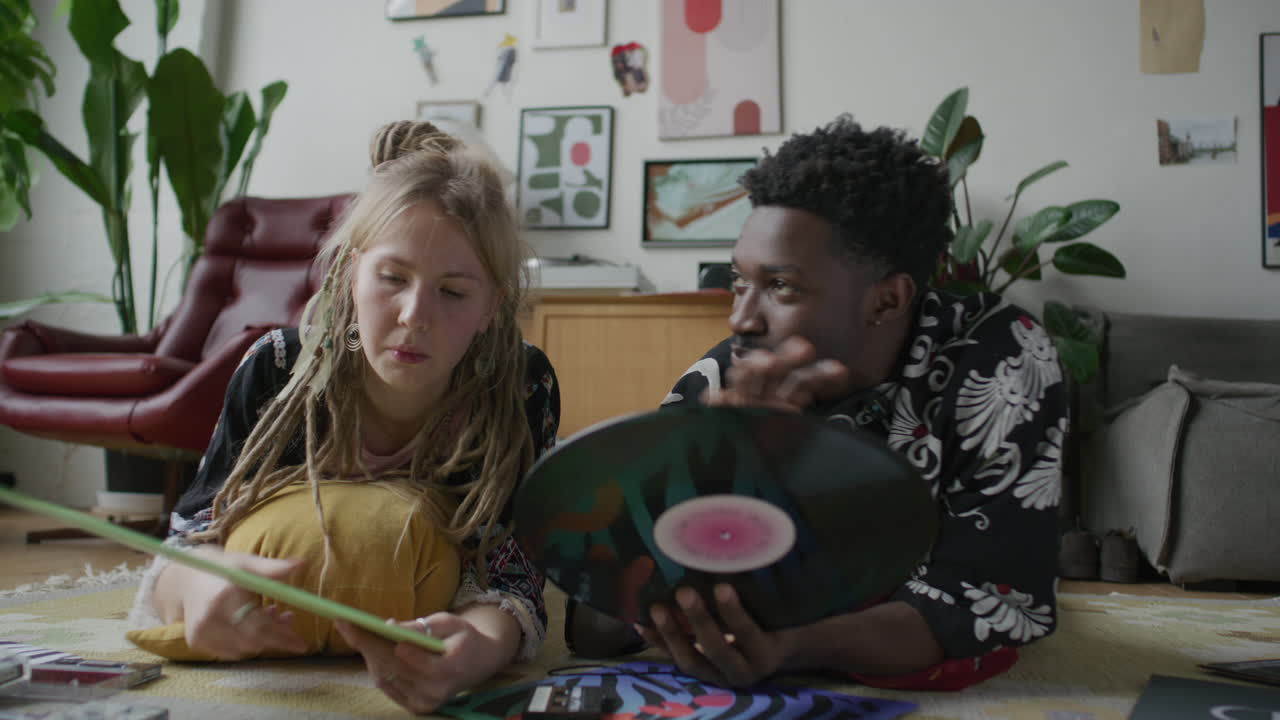 Young Man and Woman Lying on Floor at Home, Discussing Vinyl Records