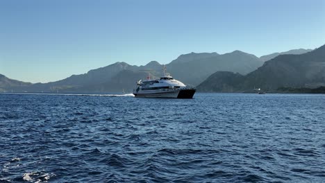 turkey, marmaris rhodos ferry entering the marmaris bay slowly on a sunny day with blue skies and no clouds. white splashes behind the ferry on deep blue calm sea.