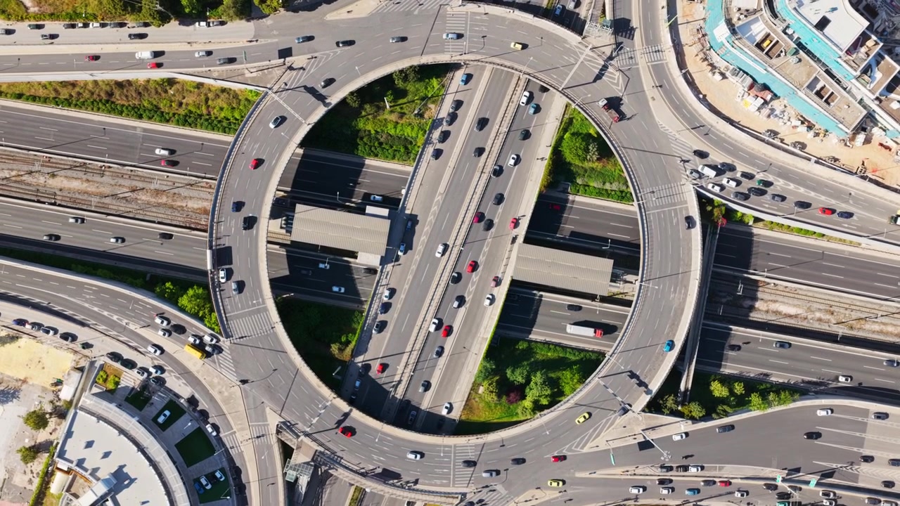 交通量の多い都市のロータリー。複雑な多層式道路ジャンクションを通過する車や車両が、現代のインフラ、交通システム、都市の交通パターンを示している。
