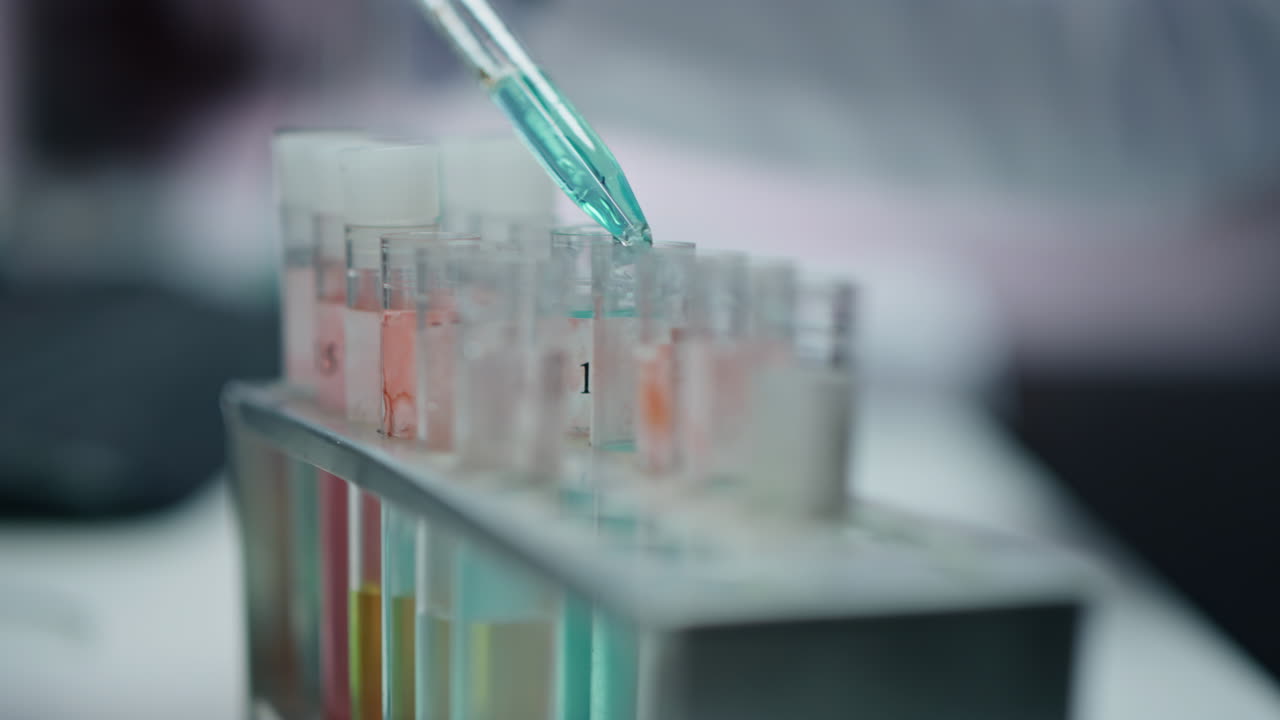 Unrecognizable scientist dripping pipette medicines to test tubes in lab closeup