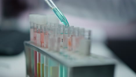 científico irreconocible goteando pipetas de medicamentos en tubos de ensayo en un primer plano de laboratorio