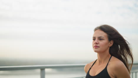 close-up of woman running outdoors with loose hair flowing in wind, displaying determination and energy in a serene environment with focus on her movements and athletic performance