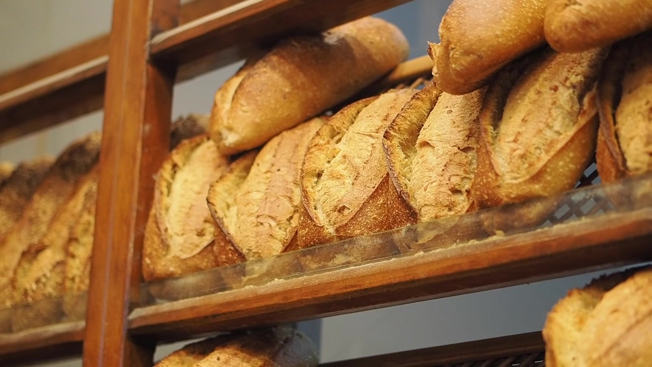 Freshly Baked Baguettes Displayed on Wooden Shelves in a Bakery
