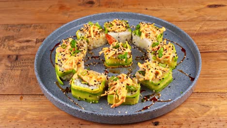 closeup of a plate of avocado sushi being removed from a wooden table in a restaurant