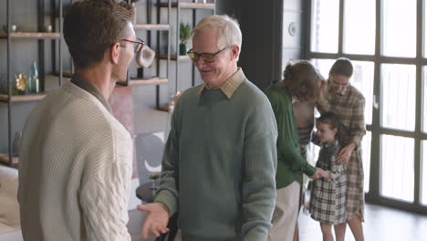 Two-Male-Relatives-Shaking-Hands-And-Hugging-Each-Other-During-A-Family-Reunion-At-Home