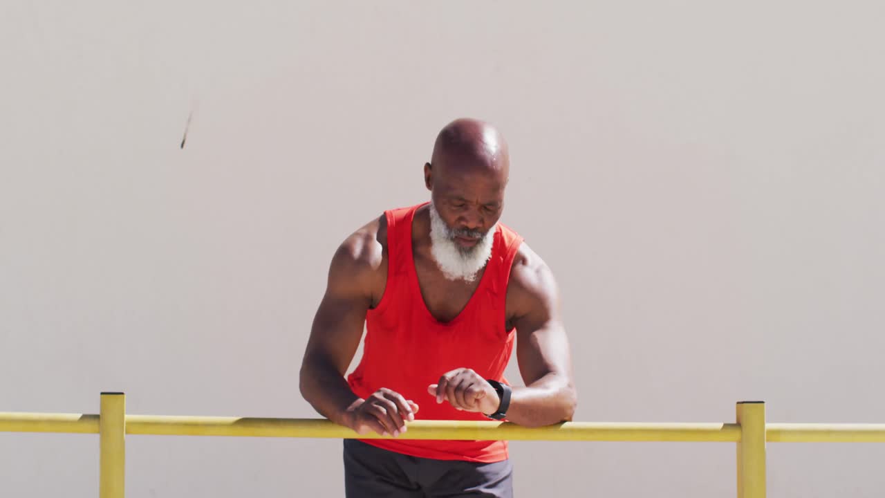 Senior african american man exercising taking a break using smartwatch